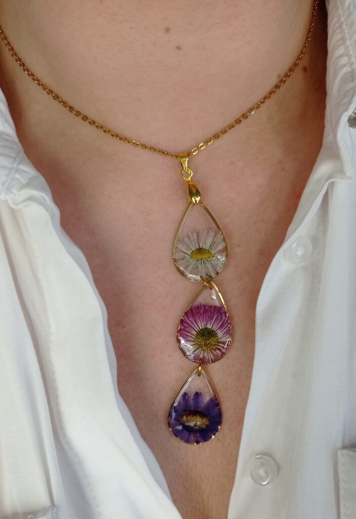 długi naszyjnik z kwiatami w kolorach białym, różowym i fioletowym każdy kwiat w osobnej złotej łezce